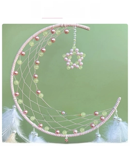 Close-up of moon dream catcher with pink ribbons, beads and soft white feathers
