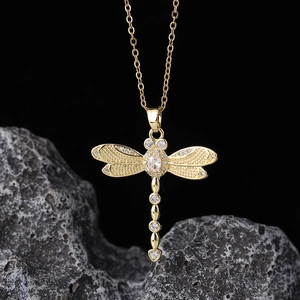 Macro detail of gold dragonfly pendant with sparkling cubic zirconia on dark stone