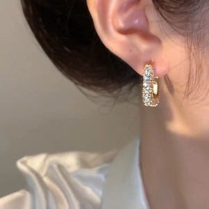 Elegant gold square hoop earrings with sparkling cubic zirconia on a female model