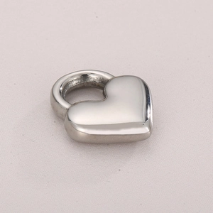 Polished silver hollow heart pendant in stainless steel on light fabric background