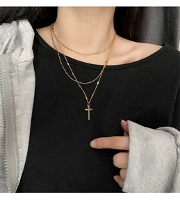Close-up of triple-layered gold titanium cross necklace set worn by a model