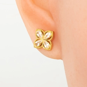 Detail of gold four-leaf clover earrings with clear zircon stones on a model
