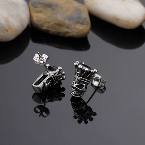 Macro view of vintage silver skull stud earring with black gemstone and crown claw