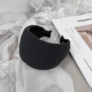 Close-up of black textured fabric headband with pleats on aesthetic magazine background