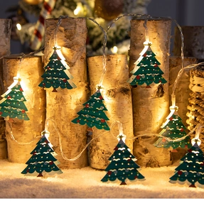 Detail of warm LED string lights with hollow green Christmas trees and golden stars