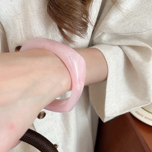 Close-up of a thick pale pink resin bangle showing smooth texture and translucent finish