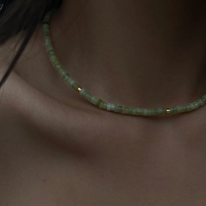 Close-up of a green natural stone beaded necklace with gold metal spacers on neck