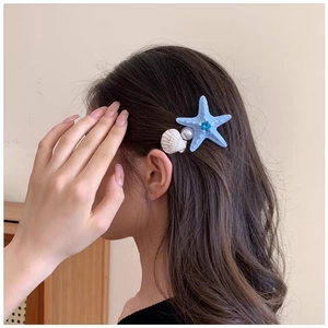 Close-up of ocean-themed starfish and shell hair clips worn on a woman's side hair