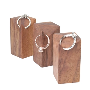 Macro shot of three wooden prism ring stands in dark walnut wood grain with metal rings
