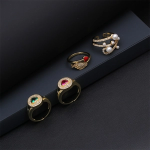Détail de bagues plaquées or avec cœurs en zircon, ailes et perles sur support noir