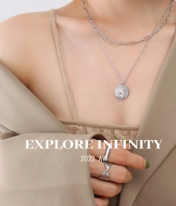 Detail of silver double-layer necklace with angel coin pendant and minimalist rings