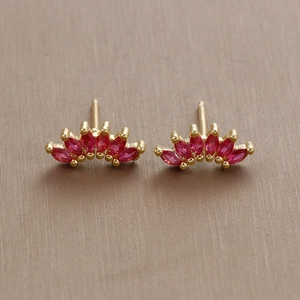 Macro detail of fan-shaped gold earrings with marquise-cut red zircon stones