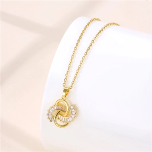 Macro shot of gold-plated knot pendant with cubic zirconia on a white display stand