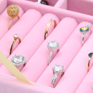 Pink velvet jewelry box with glass lid organizing various rings and stud earrings