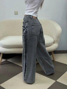 Detailed view of gray wide-leg jeans with unique frayed side seams and raw edge finish