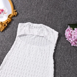 Détail de la robe courte en dentelle blanche ajourée avec tissu texturé et design bustier