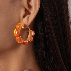 Close-up of amber resin geometric C-shaped earrings worn by a model for a chic look