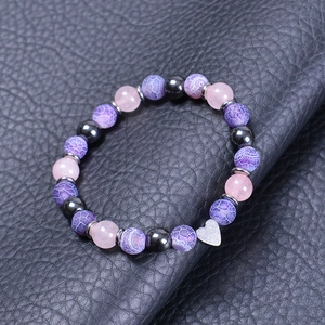 Macro detail of natural stone beaded bracelet with purple agate and silver heart charm