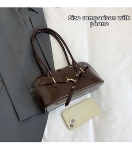 Deep brown glossy leather shoulder bag shown next to a smartphone for size comparison