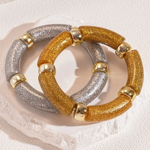 Detail of glitter bead bracelets with gold accents on a white stone display stand