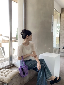 Close-up of a purple woven bucket bag styled with a white puff sleeve top and blue jeans