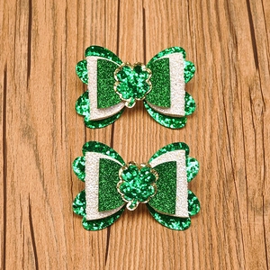 Detail of St. Patrick's Day glitter bows with shamrock centers on wood background