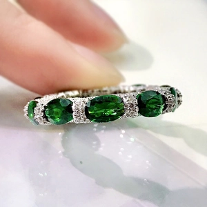 Macro detail of silver ring with oval green gemstones and pave set cubic zirconia