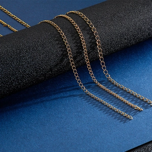 Close-up of four golden stainless steel curb chains displayed on a textured black stand