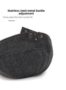 Detail view of adjustable stainless steel buckle on dark grey wool newsboy cap