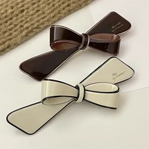 Detail of glossy resin bow hair clips in coffee brown and cream with black border
