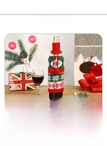 Close-up of knitted Christmas wine bottle cover with snowflakes and festive red pom-poms