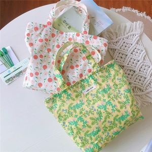 Détail de sacs cabas en toile de coton florale avec étiquette sur table blanche