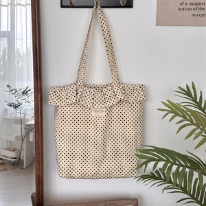 Polka dot canvas tote bag with ruffled edges hanging on a wall in a minimal home setting