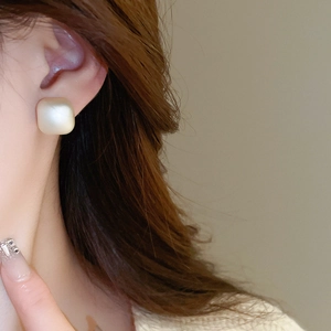 Close-up of matte beige square stud earring on a model for a chic french minimalist style