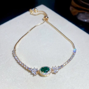 Nahaufnahme eines eleganten Goldarmbands mit grünem ovalem Edelstein und Zirkonia.