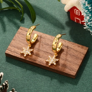 Festive gold snowflake hoop earrings with sparkling zircons on a dark wood background