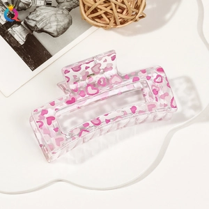 Close-up of a pink heart pattern hair claw clip on a white decorative tray