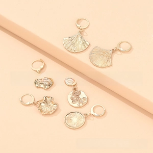 Detailed view of gold alloy dangle earrings with floral motifs and textured metal charms