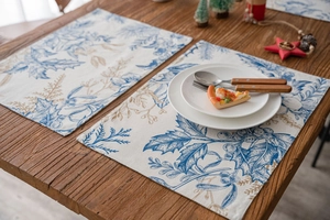 Close-up of double-layered Christmas placemats with festive berry and leaf print