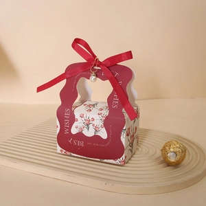 Detail of red floral wedding candy box with gold text and elegant pearl pin accessory