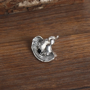 Macro view of a silver witch hat brooch with gemstones on a dark wooden surface