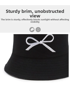 Detailed close-up of a black sun hat with white bow embroidery and a firm brim texture