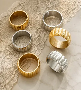 Detail of wide textured metal rings in gold and silver finish with vertical wavy relief