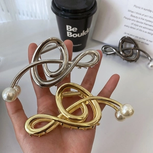 Close-up of metallic music note hair claws in gold, silver and grey with pearl details