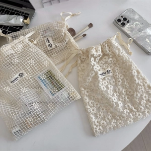 Close-up of delicate daisy embroidery on beige mesh lace drawstring storage bag