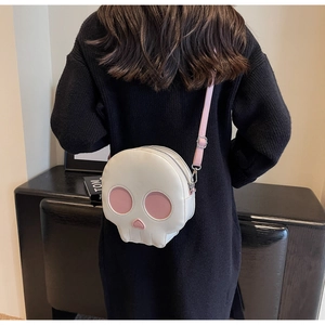 Detail of creative skull crossbody bag in white and pink faux leather worn by a model