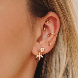 Close-up of gold S925 silver hoop earrings with zircon bee and daisy charms on ear
