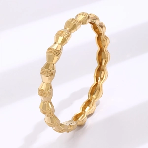 Macro detail of gold geometric bangle featuring frosted finish and faceted surface