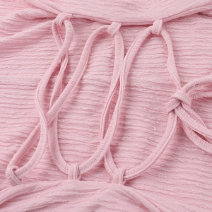 Detail of pink pleated fabric featuring intricate multi-strap woven design on long dress