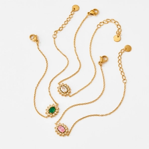 Vintage French gold bracelets with emerald, pink, and white zircons on a white background